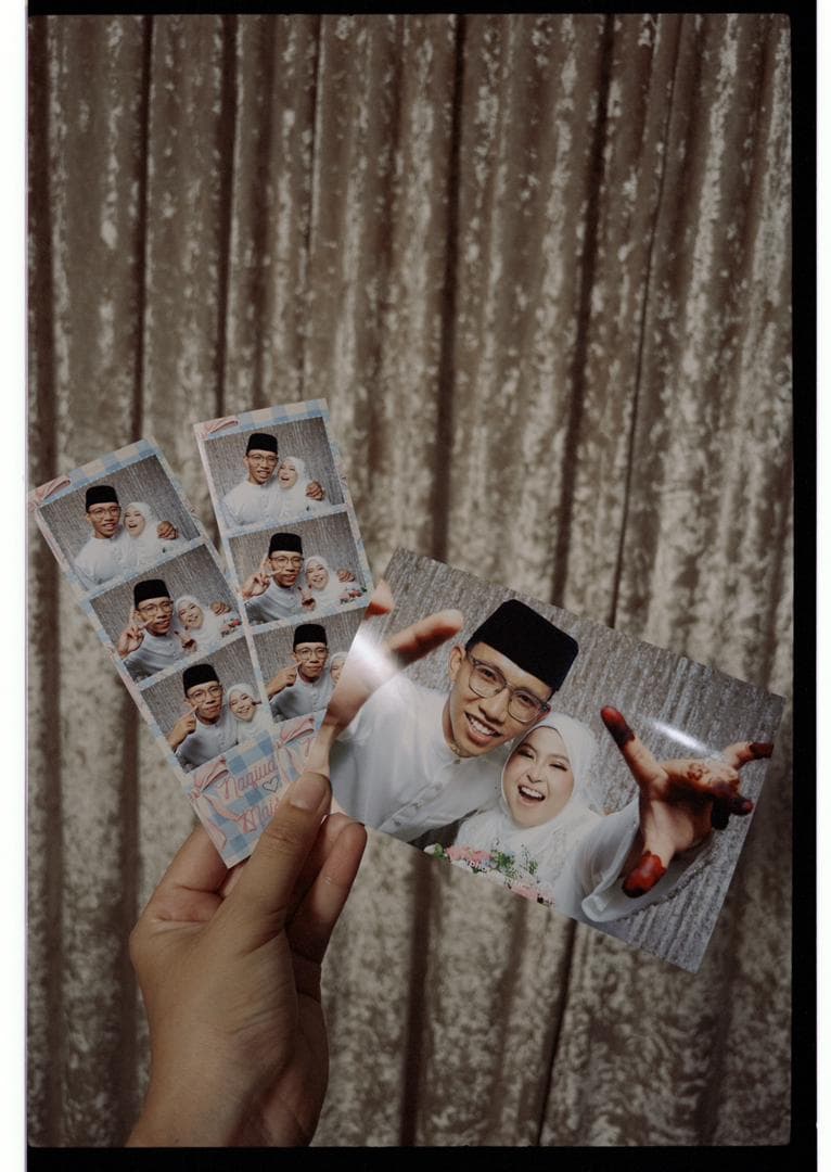 Guest holding printed photostrips in front of the booth